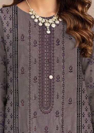 Woman wearing a gray embroidered outfit with a necklace, surrounded by purple flowers.
